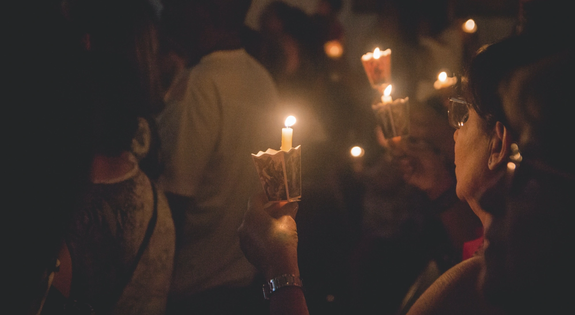 People holding candles at a community gathering.